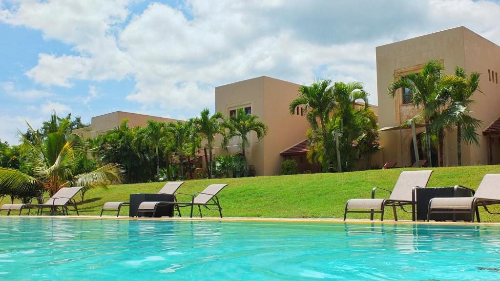 a swimming pool with chairs and a building at Vipingo Ridge-Swahili Villa in Mombasa