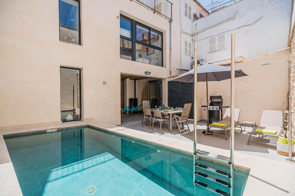 a swimming pool in front of a house with a table and chairs at CASA OASIS in Pollença