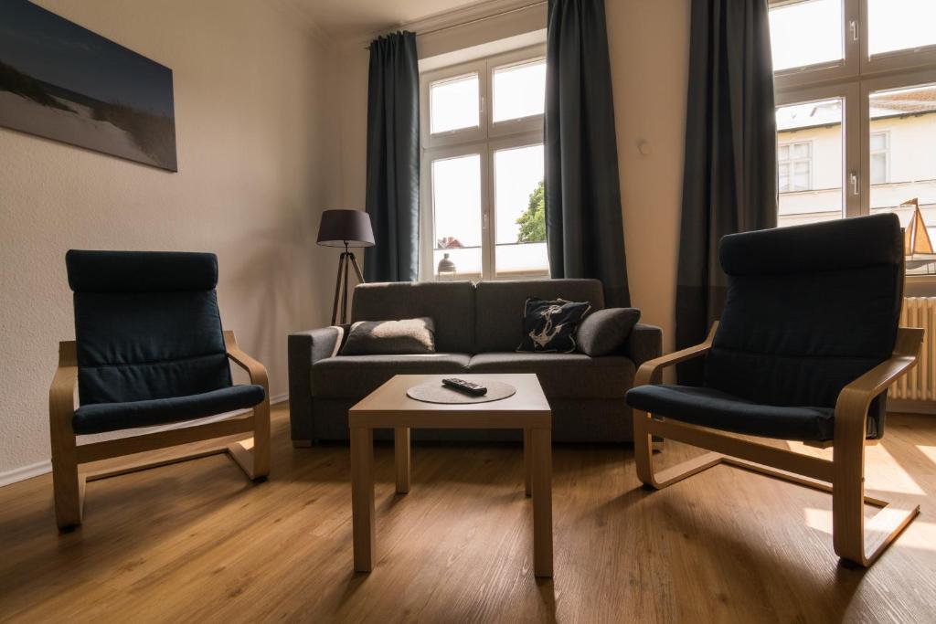 uma sala de estar com um sofá e duas cadeiras e uma mesa em Ferienwohnung Sundkieker em Stralsund