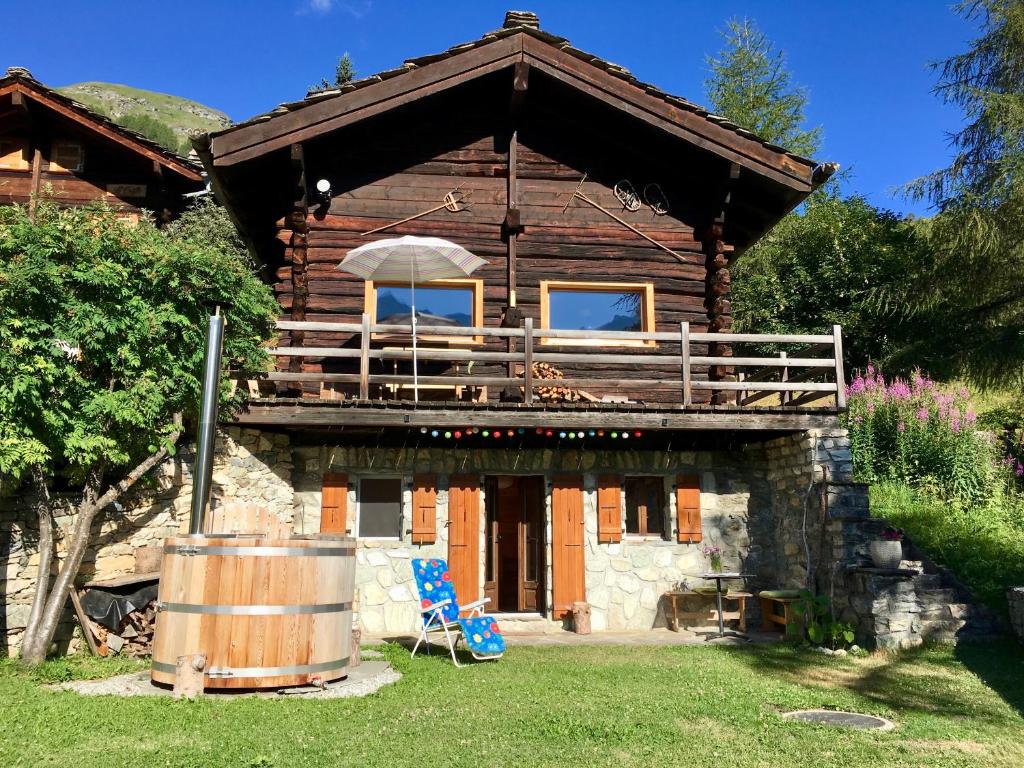 a log cabin with a deck and a chair and a barrel at Grand Pra in Haudères