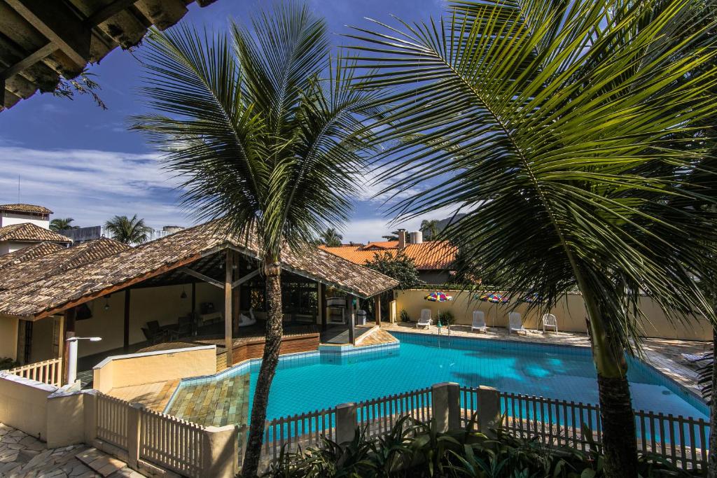 a swimming pool with two palm trees in front of a house at Pousada Brig Maresias in Maresias
