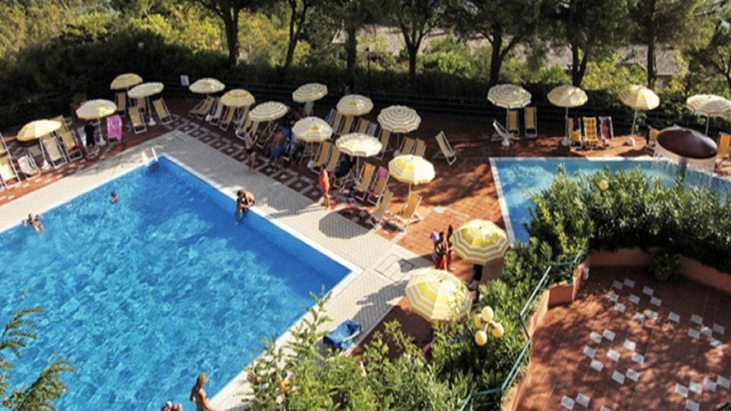 uma piscina com um monte de guarda-sóis, mesas e cadeiras em Residence Pianeta Maratea em Maratea