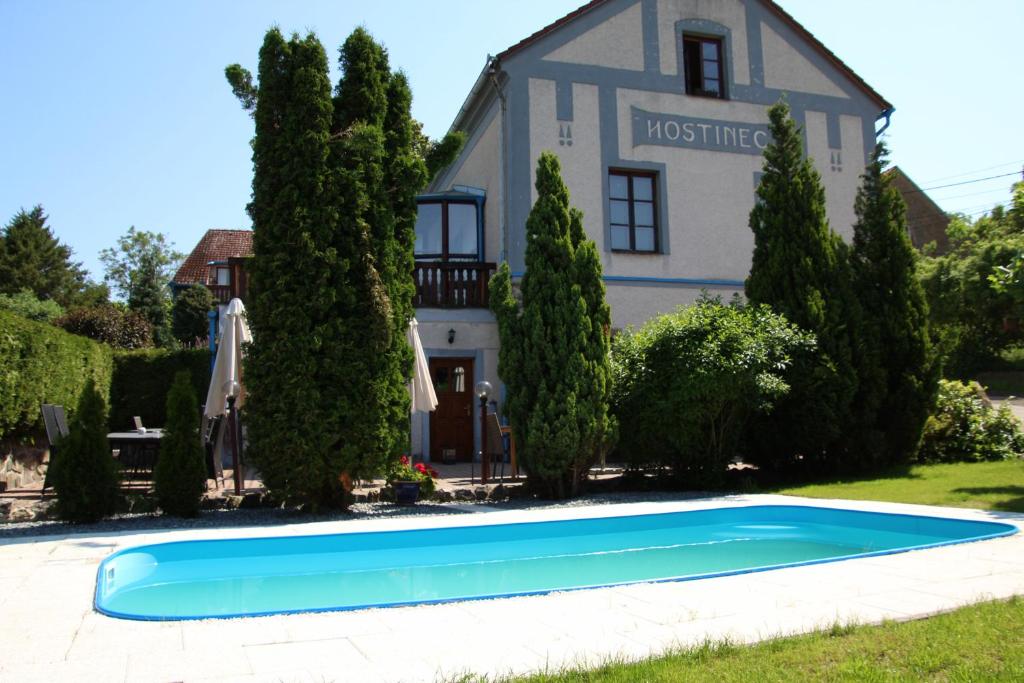 a blue swimming pool in front of a house at Penzion Stranny in Stranný