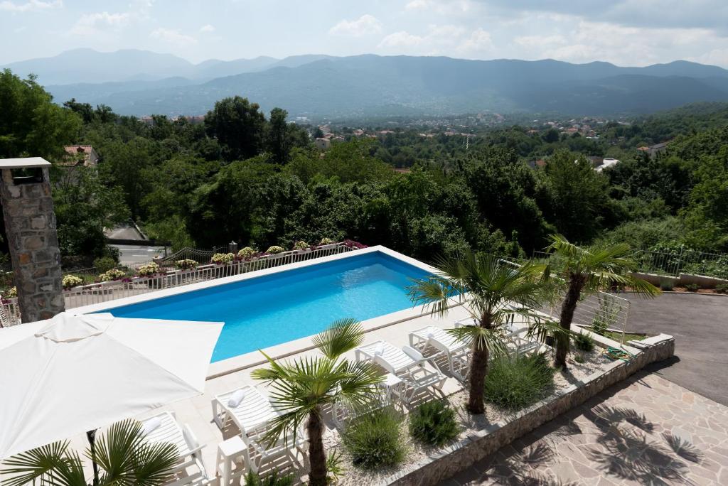 a swimming pool with chairs and a view of the mountains at Castua in Kastav