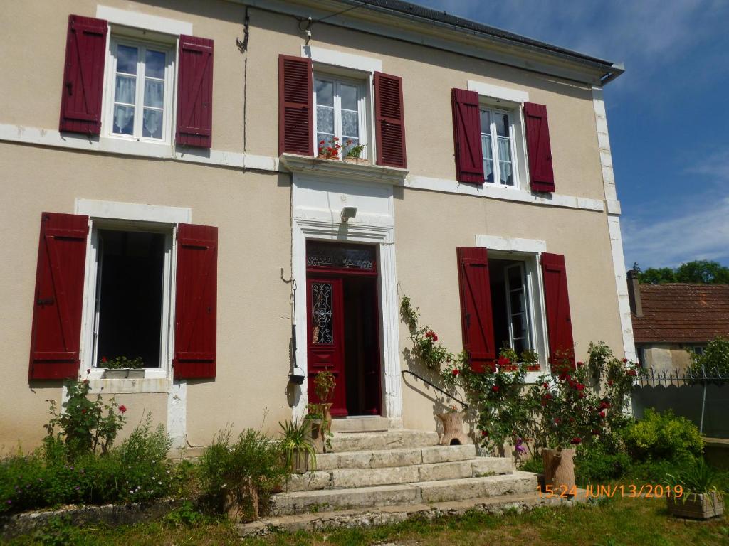 uma casa com persianas vermelhas e uma porta vermelha em Gite des Belles Fontaines em Druyes-les-Belles-Fontaines