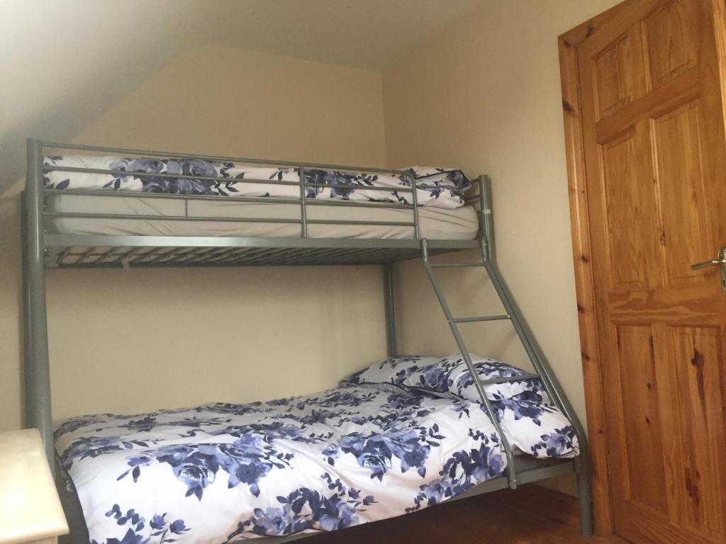 a bedroom with a bunk bed with blue and white sheets at 39 woodview in Listowel