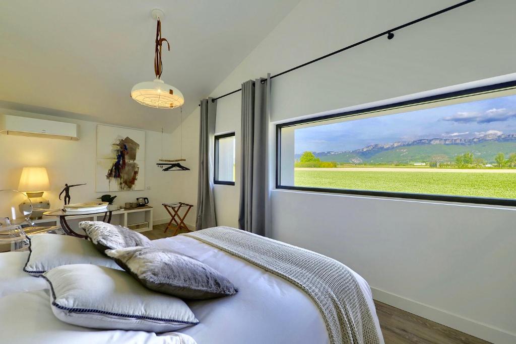 a bedroom with a large window and a bed with pillows at Terre de Sienne in Charpey