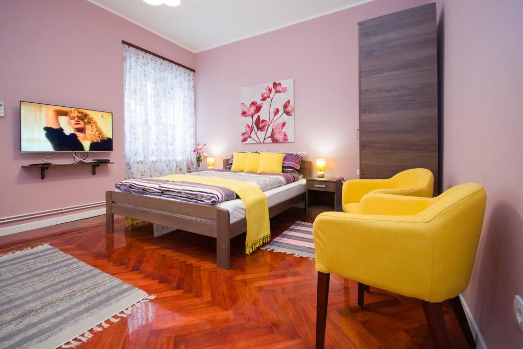 a bedroom with a bed and two yellow chairs at Romance in Belgrade