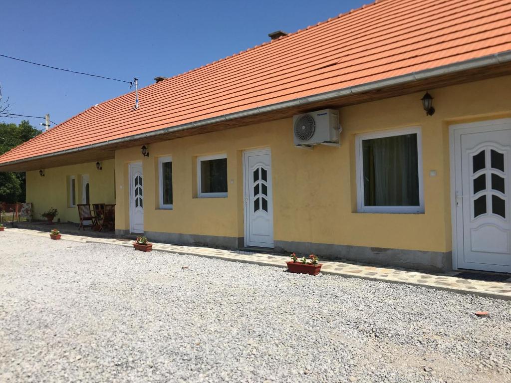 un edificio amarillo con techo naranja y puertas blancas en Napfény Apartman, en Sárospatak
