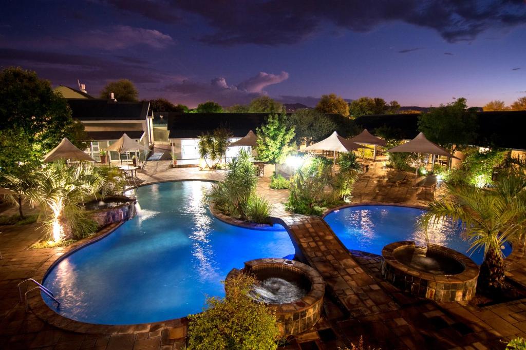 una vista aérea de una piscina por la noche en Arebbusch Travel Lodge, en Windhoek