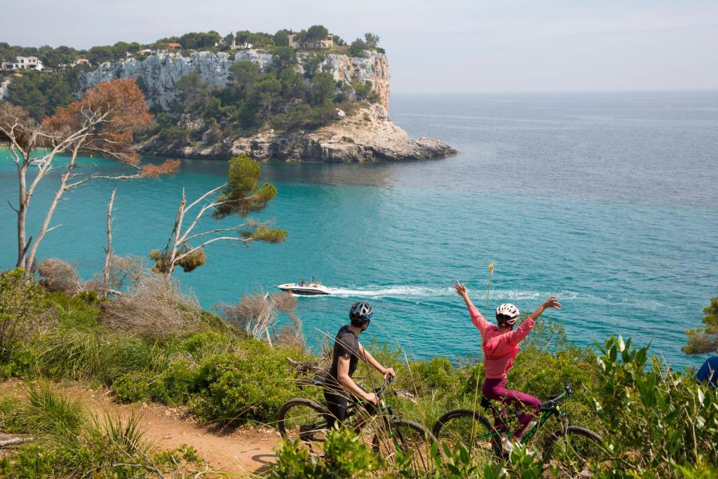two people riding bikes on a hill near the ocean at ARTIEM Audax - Adults Only in Cala Galdana