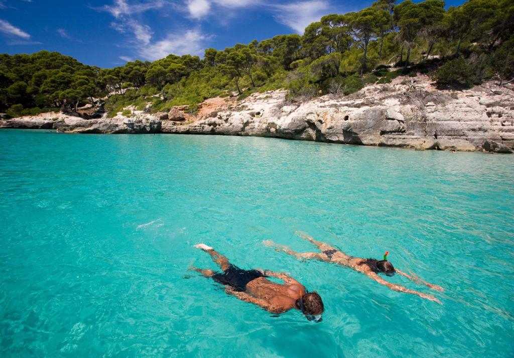 two people laying in the water in the ocean at ARTIEM Audax - Adults Only in Cala Galdana