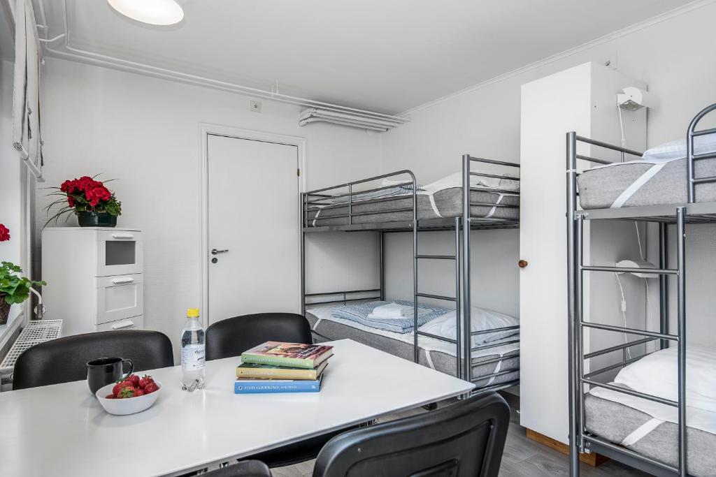 Pokój ze stołem, krzesłami i łóżkami piętrowymi w obiekcie Tallbackens Gård & Vandrarhem w mieście Svärtinge