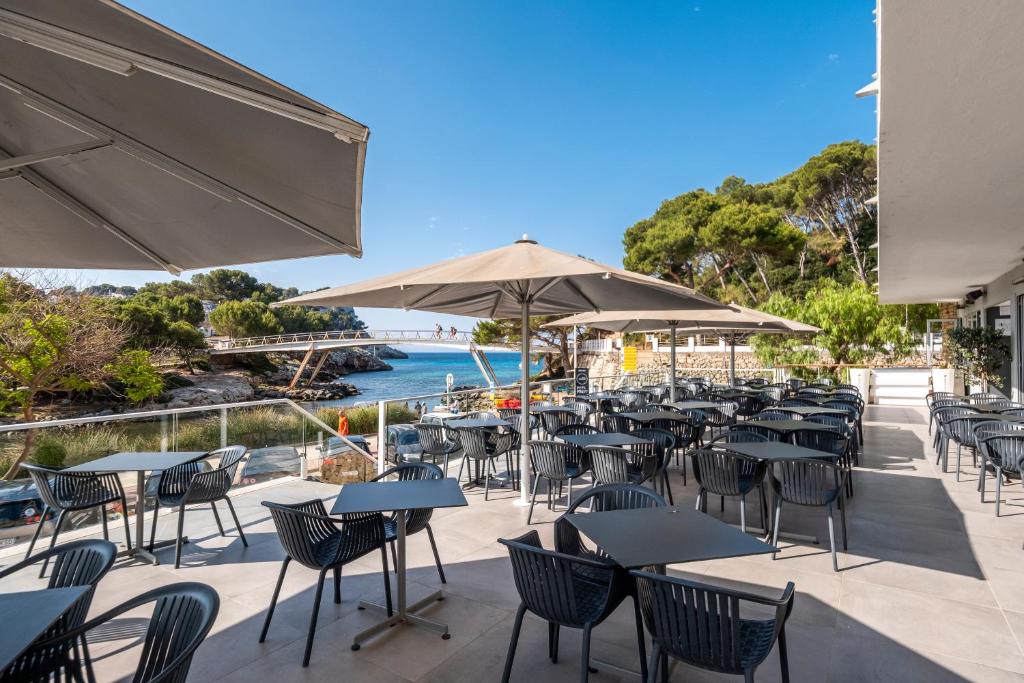 an outdoor patio with tables and chairs and the ocean at ARTIEM Audax - Adults Only in Cala Galdana