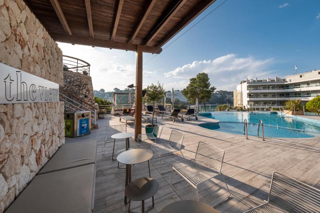 a patio with chairs and a swimming pool at ARTIEM Audax - Adults Only in Cala Galdana