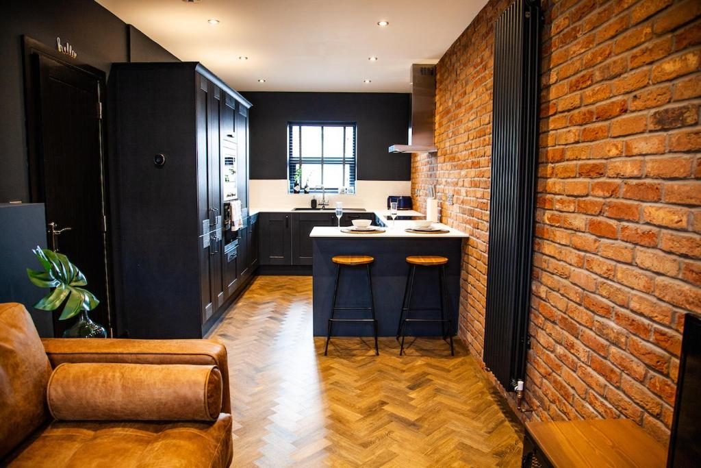 a kitchen with a bar and a brick wall at The Barbershop Apartments in Manchester
