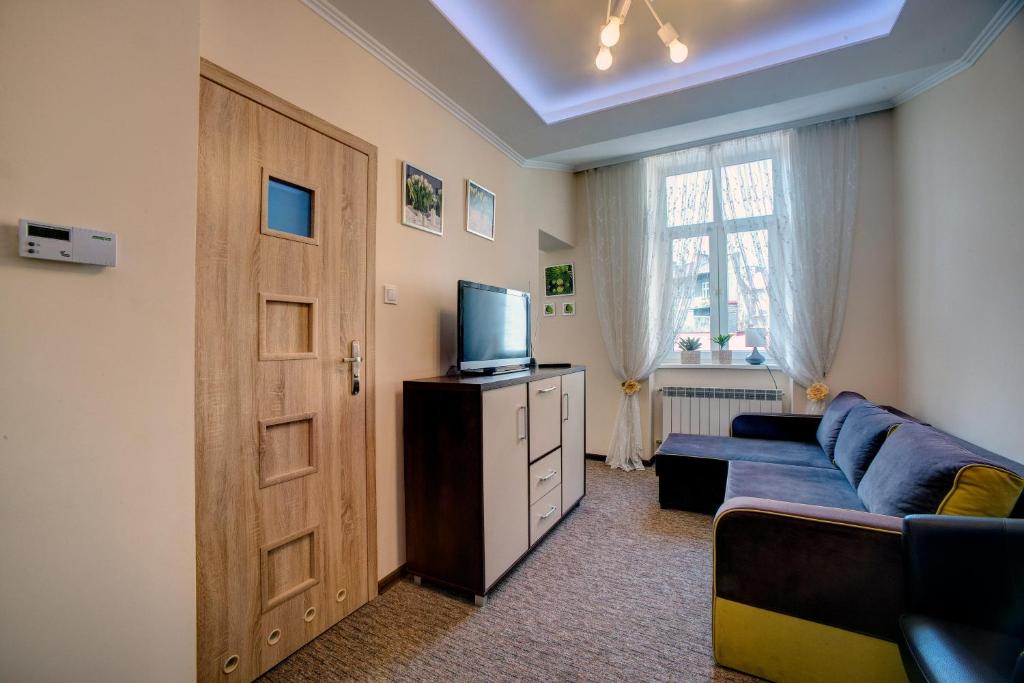 a living room with a blue couch and a television at APARTAMENTY in Przemyśl