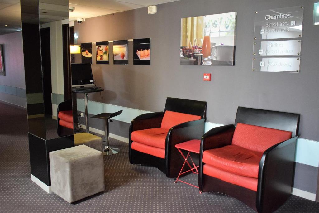 a waiting room with red chairs and a table at Logis Hôtel La Fauceille in Perpignan