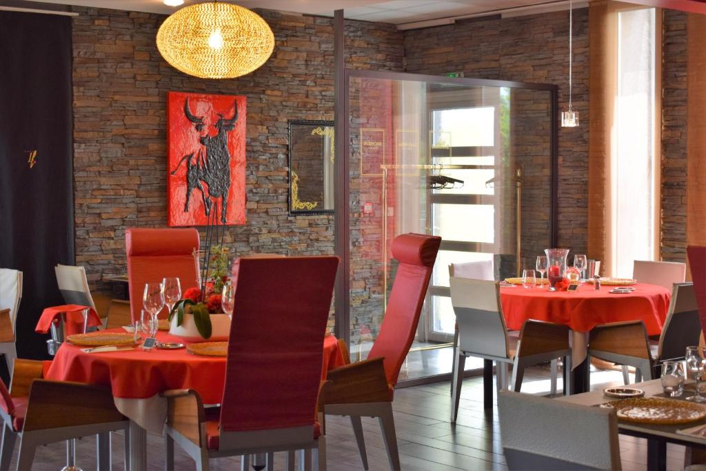 a dining room with red tables and chairs and a brick wall at Logis Hôtel La Fauceille in Perpignan