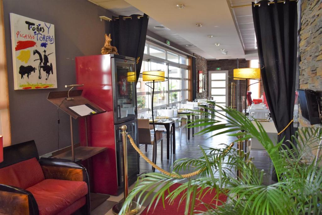 a restaurant with a red couch and tables and plants at Logis Hôtel La Fauceille in Perpignan