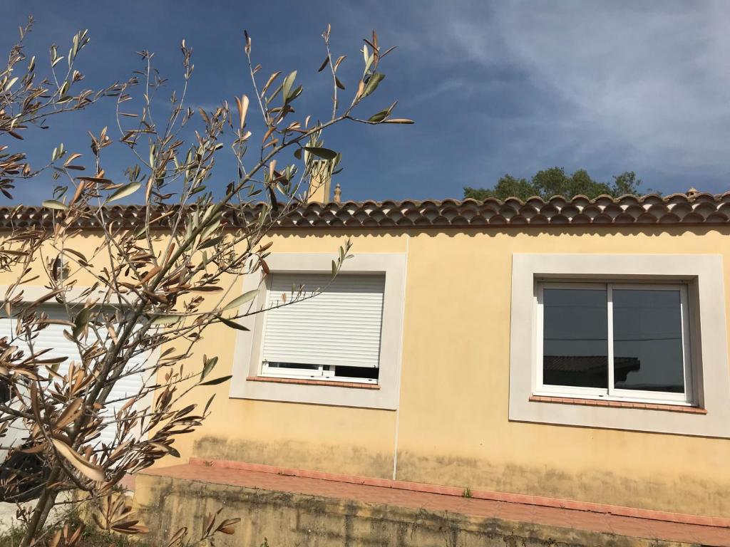 una casa con dos ventanas y un árbol en Appartement à la mer, en Le Grau d'Agde