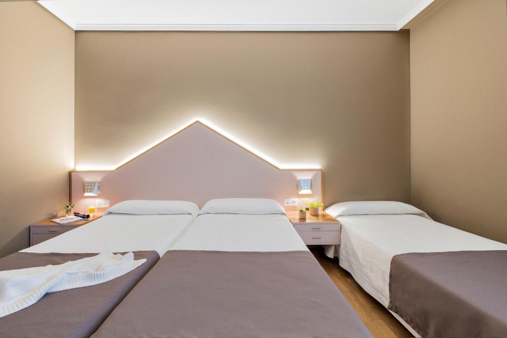 duas camas num pequeno quarto com duas lâmpadas em La Casa del Patrón em Murguía