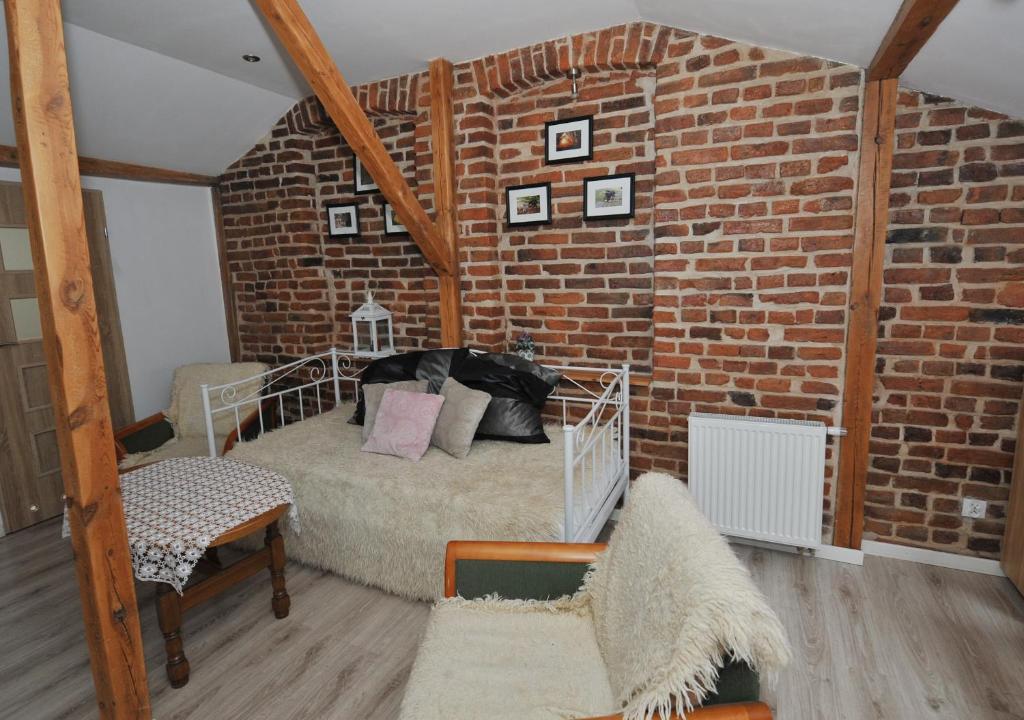 a room with a brick wall with a bed and chairs at Zakątek Alpaka in Będzin