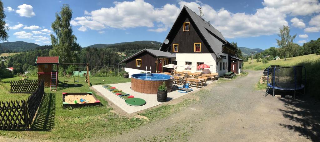 uma casa com um parque infantil e um parque de diversões em Penzion Slunečnice em Rokytnice nad Jizerou