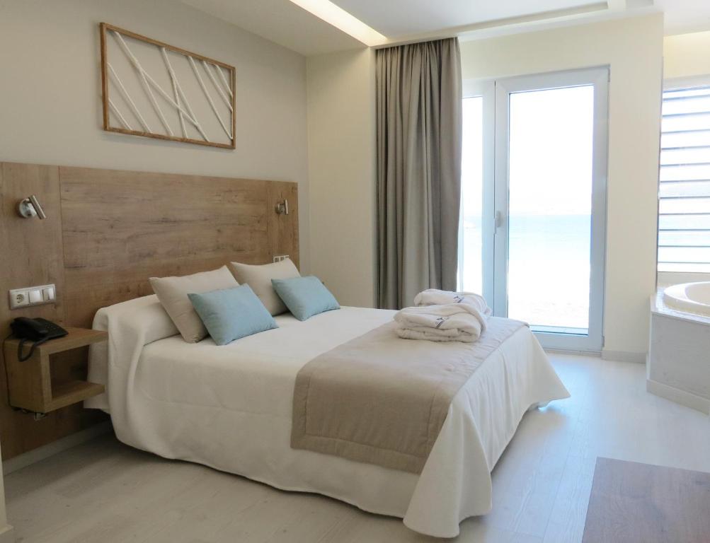 A bed or beds in a room at Hotel Boutique O Náutico Laxe