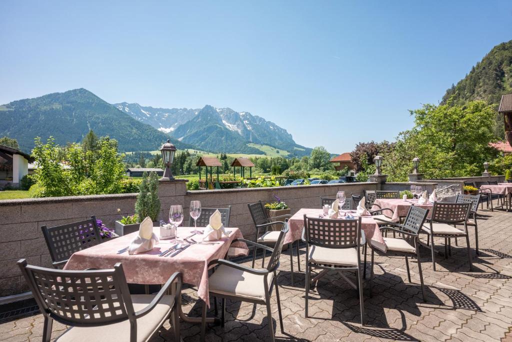 a patio with tables and chairs with mountains in the background at Hotel Walchseer Hof in Walchsee