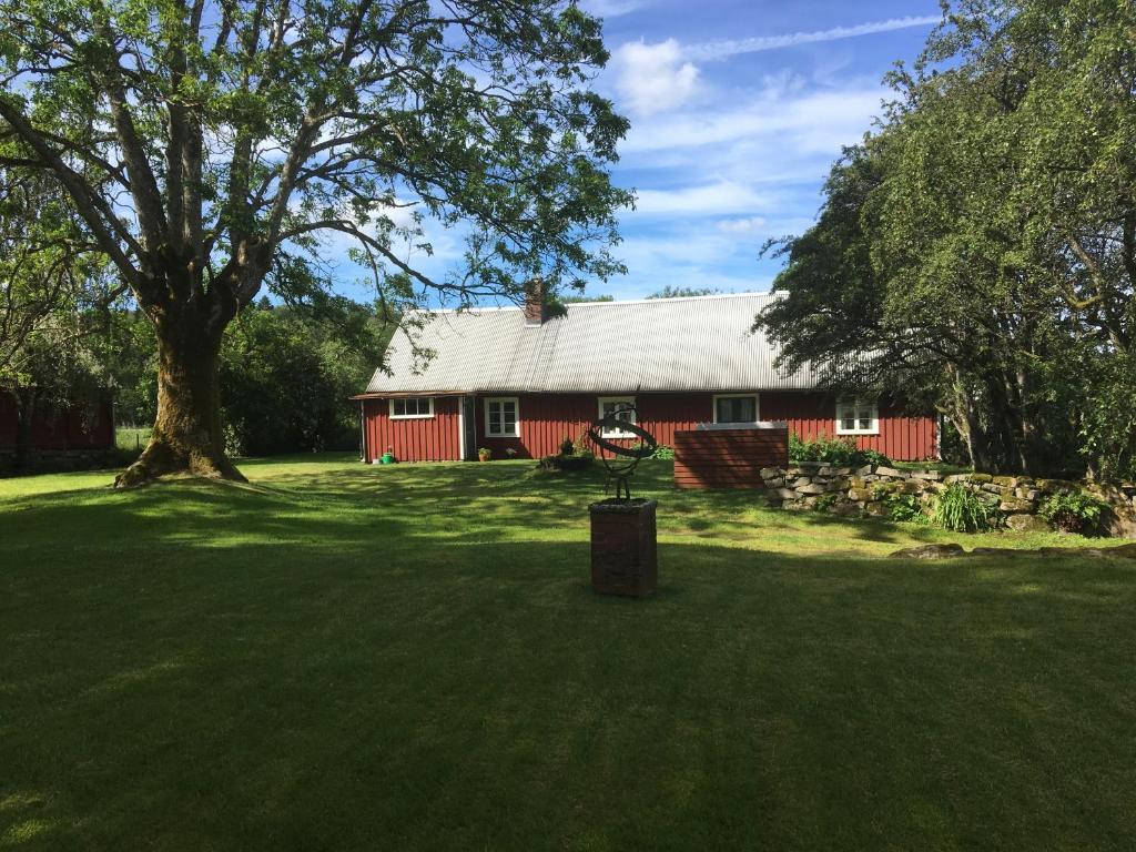 a red barn with a tree in front of it at Tubbared. in Ullared