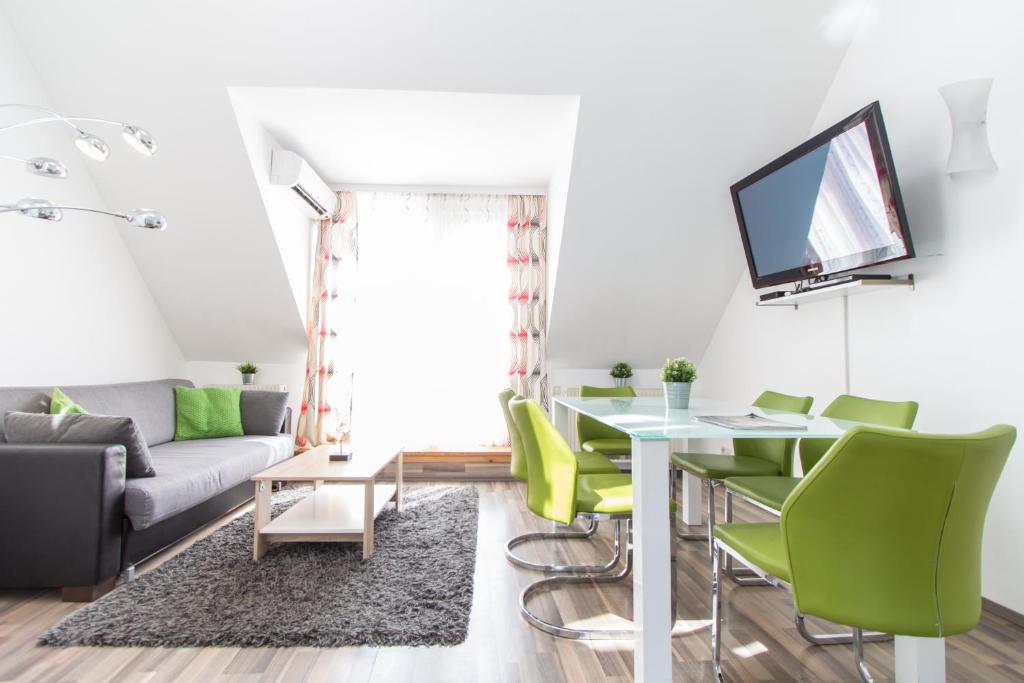 a living room with a table and green chairs at Karmeliter Flat | contactless check-in in Vienna