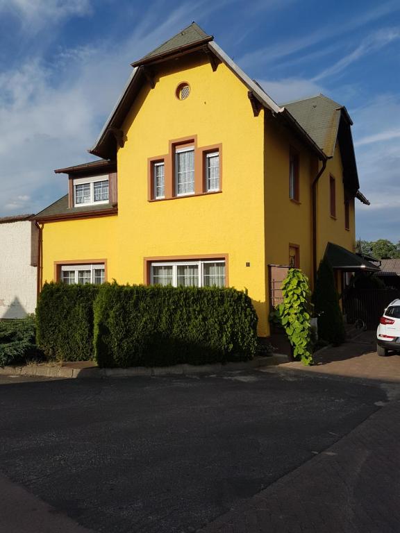 uma casa amarela com um telhado preto em Ferienwohnung Elbblick em Dessau