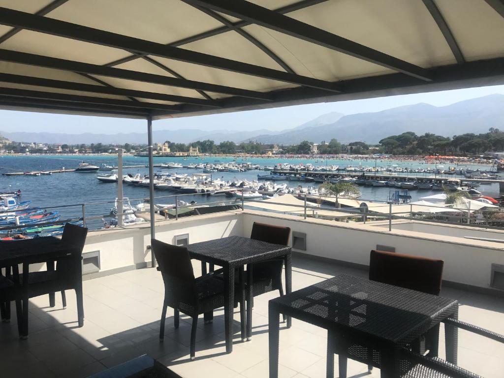 un balcone con tavoli, sedie e un porto turistico di b&b Simpaty a Mondello