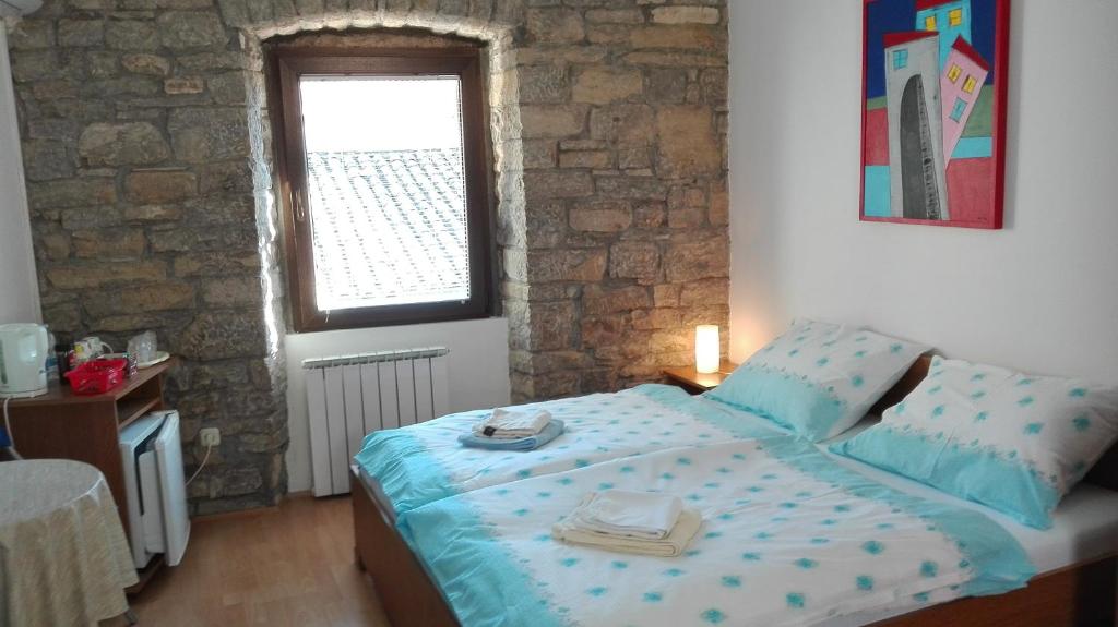 Schlafzimmer mit einem Bett mit blauer Bettwäsche und einem Fenster in der Unterkunft Rooms Svalina Adults Only in Grožnjan