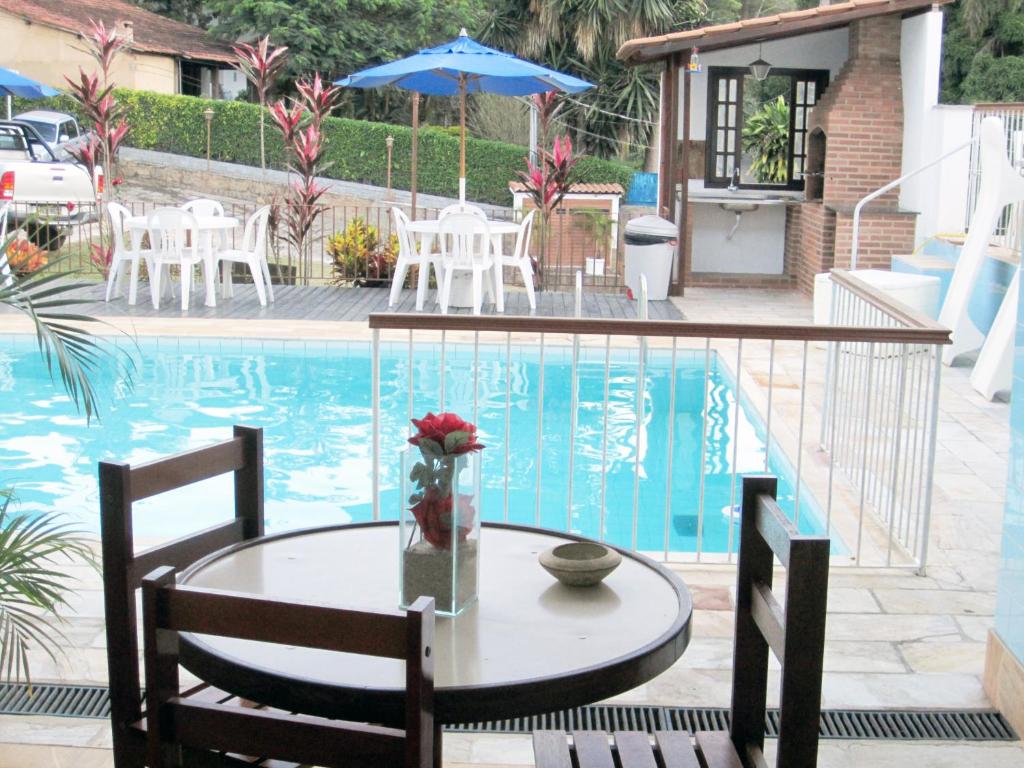 a table and chairs next to a swimming pool at Pousada das Rosas in Miguel Pereira