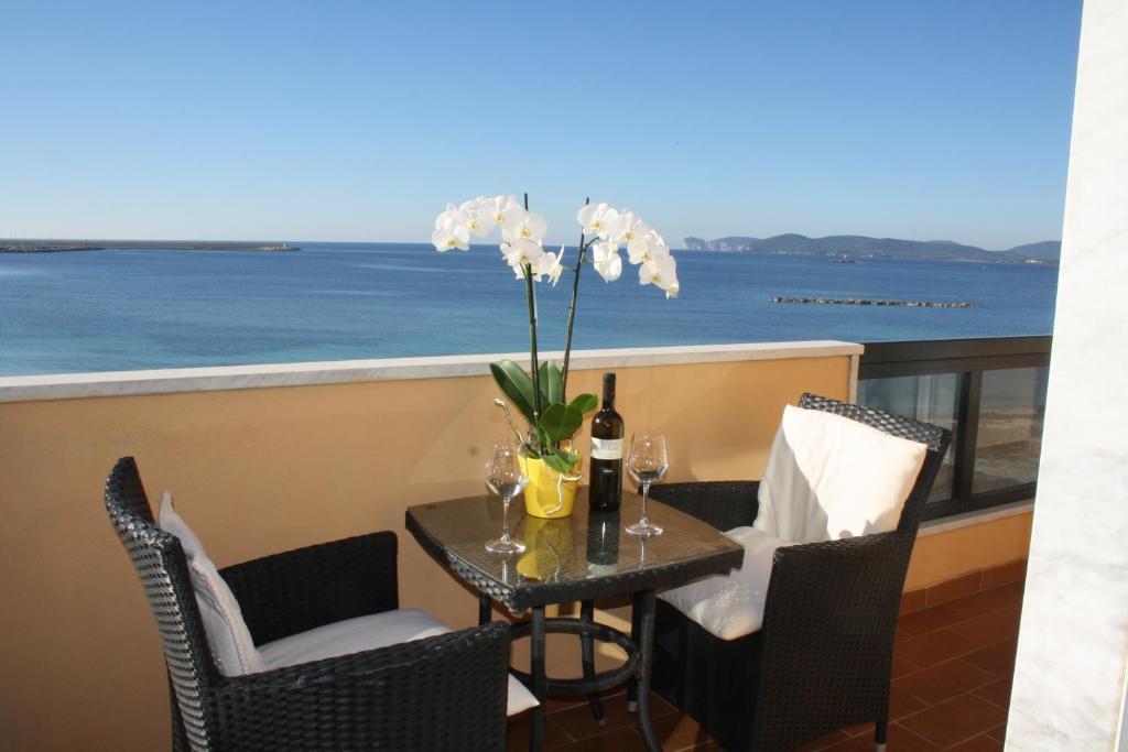 a table with a bottle of wine and flowers on a balcony at Appartamenti Sole 1 in Alghero