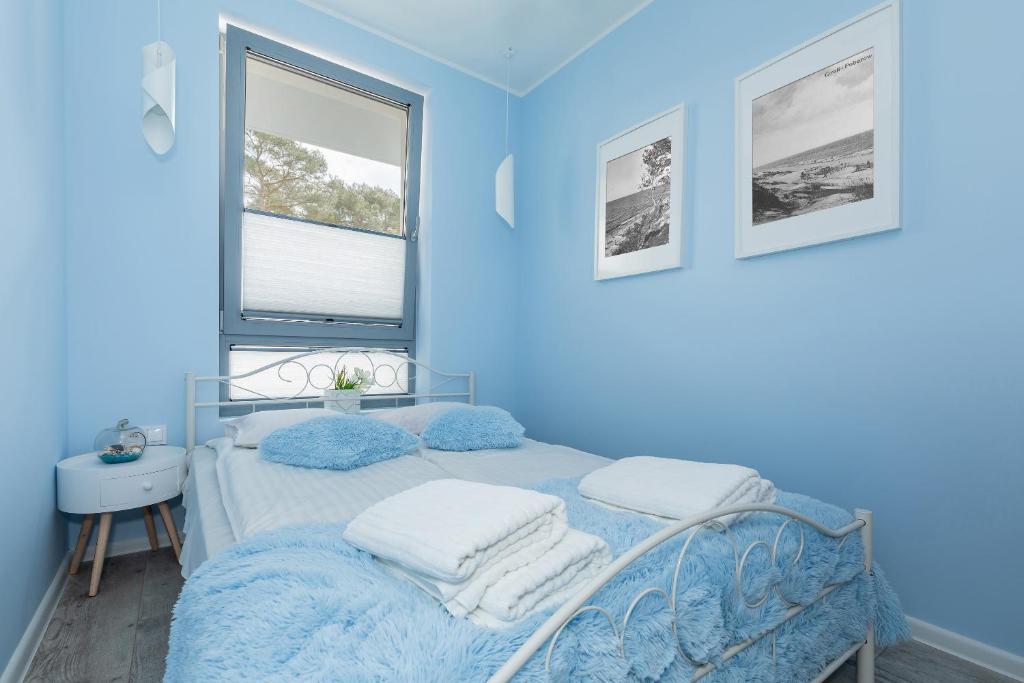 a blue bedroom with a bed with towels on it at Villa Ula Apartament in Pobierowo