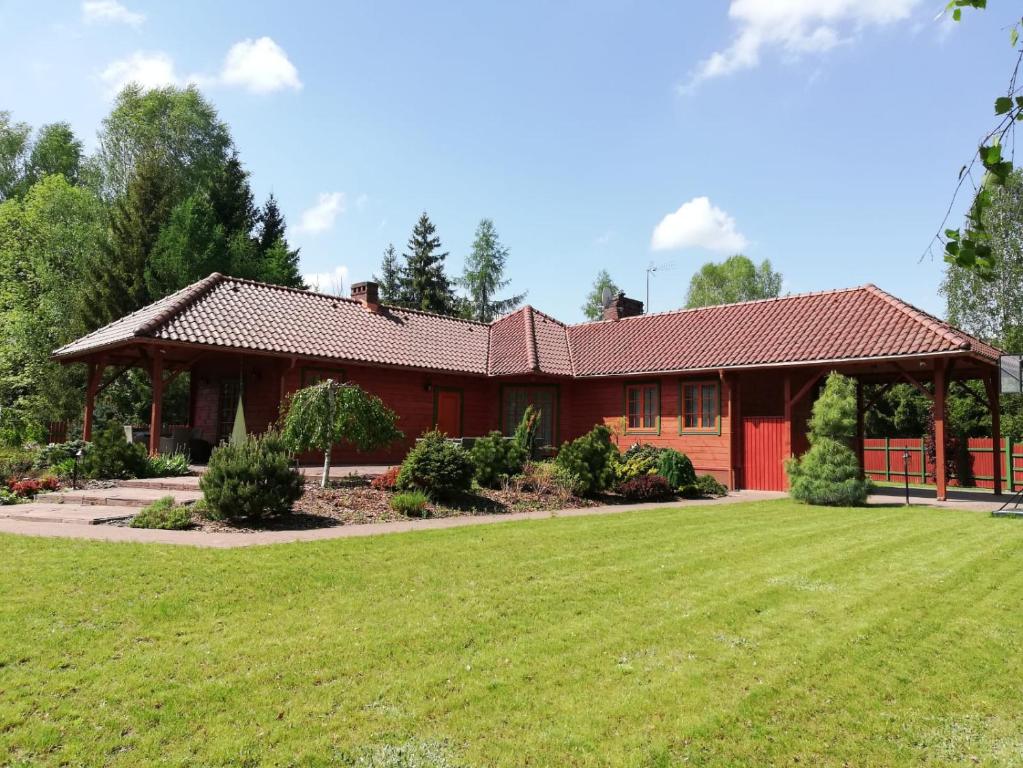 a red house with a green lawn in front of it at Wikno Dom wakacyjny in Wikno