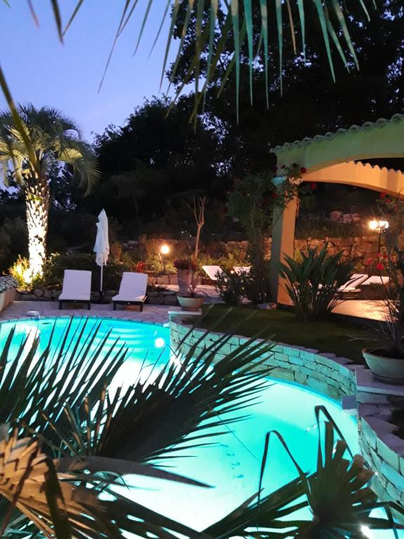 a swimming pool at night with chairs and palm trees at La Dolce Vita Opio in Opio