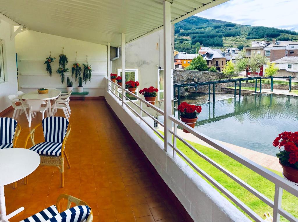 een balkon met tafels en stoelen en uitzicht op een rivier bij Casa de la Playa in Vega de Espinareda