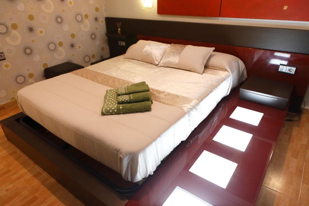 Una cama con dos toallas verdes encima. en The Victoria Apartament in Hellín, en Hellín