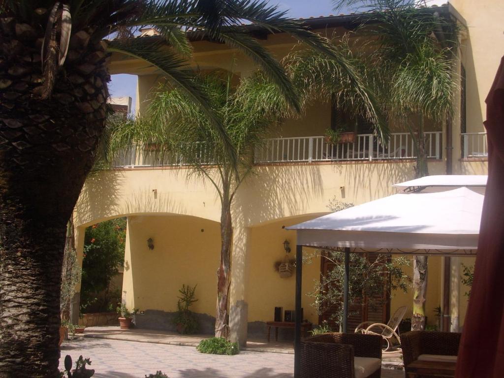 uma palmeira em frente a um edifício amarelo em B&B Valoroso Village em Licata
