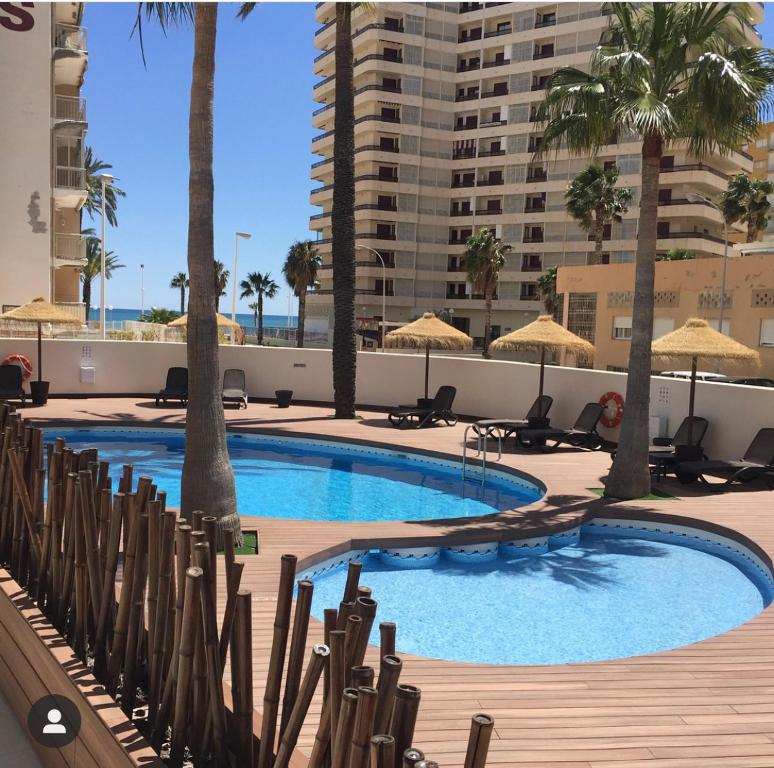 uma piscina com cadeiras e palmeiras e um edifício em Hotel Santamarta em Cullera