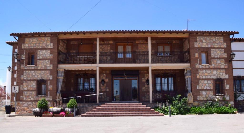 un gran edificio de ladrillo con escaleras delante en HOSTAL RESTAURANTE SAN ISIDRO en Quintanar de la Orden