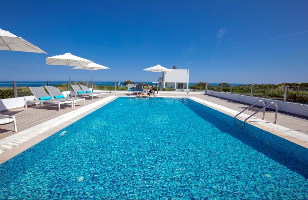 basen z leżakami i parasolami w budynku w obiekcie Aegean Horizon Beachfront Villas w mieście Jenadi