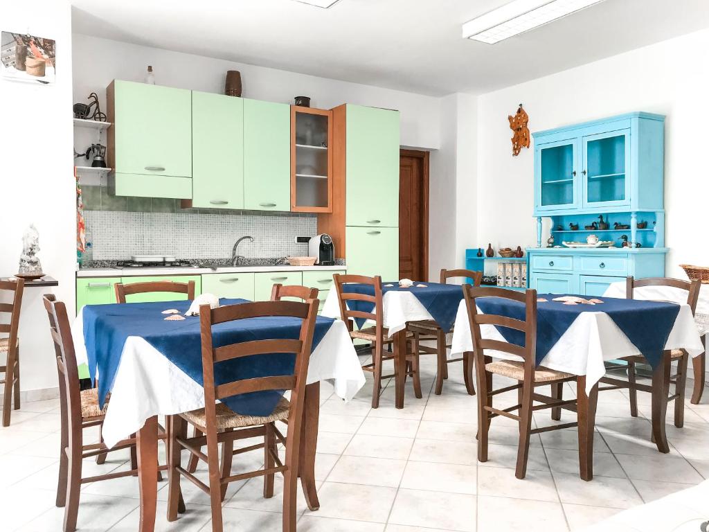 - une cuisine avec des tables et des chaises bleues dans une pièce dans l'établissement S'Aposentu, à Muravera
