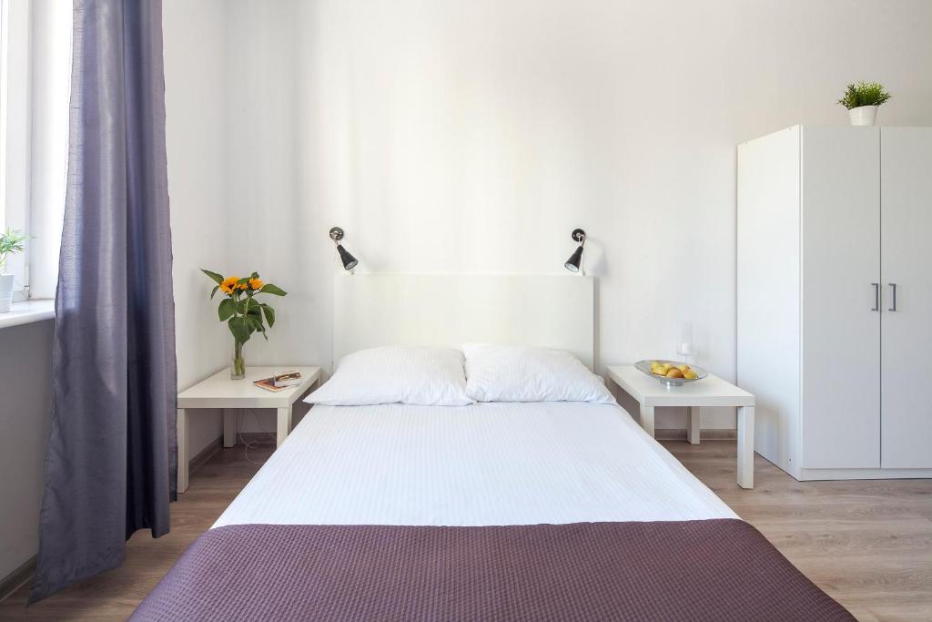 Sleepy3city Apartments 10 Lutego 23 في غدينيا: غرفة نوم بيضاء مع سرير وطاولتين