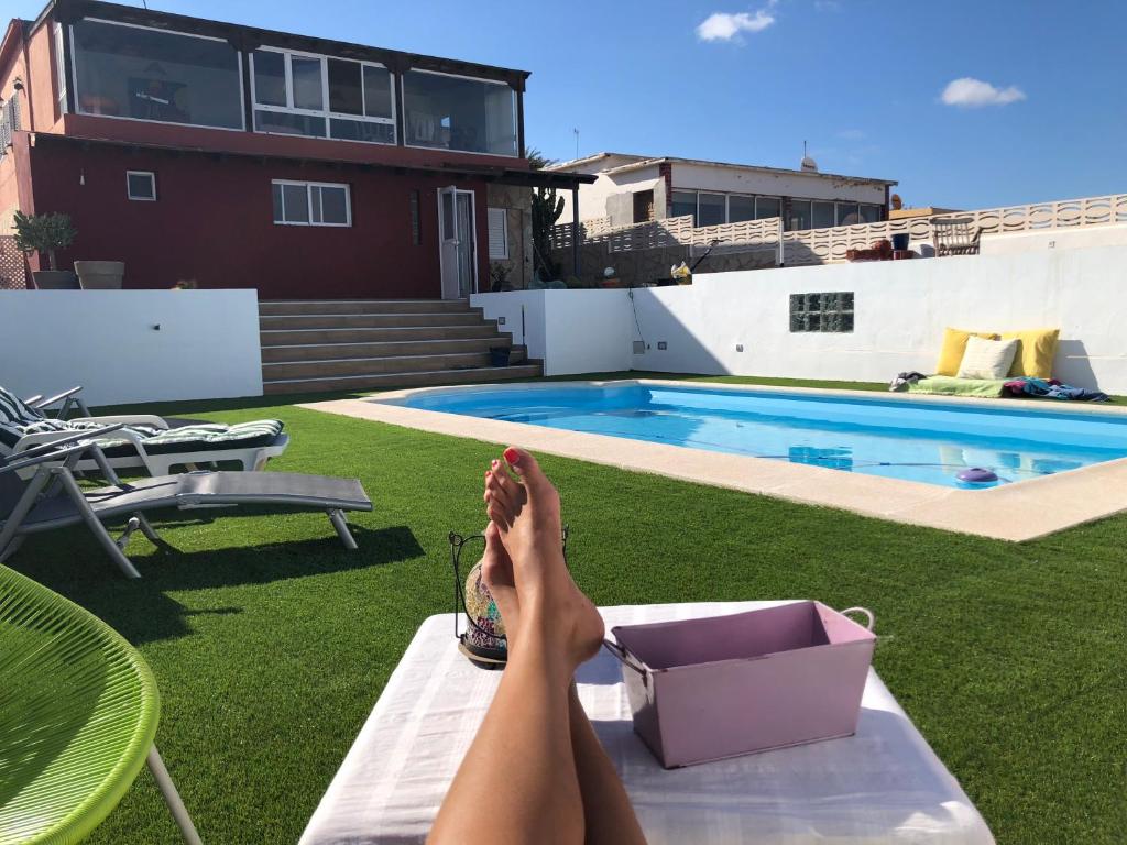 una persona con los pies en una mesa junto a una piscina en El atardecer, en Puerto del Rosario