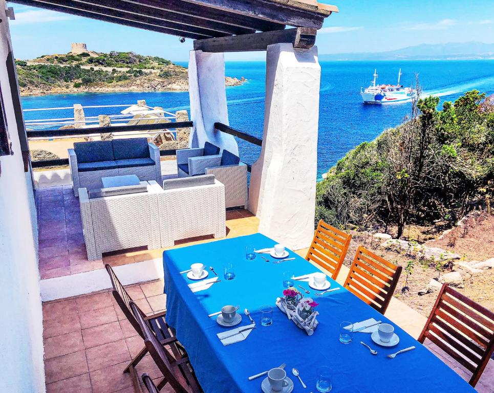 a blue table on a balcony with a view of the ocean at Villa Elena B&B experience in Santa Teresa Gallura